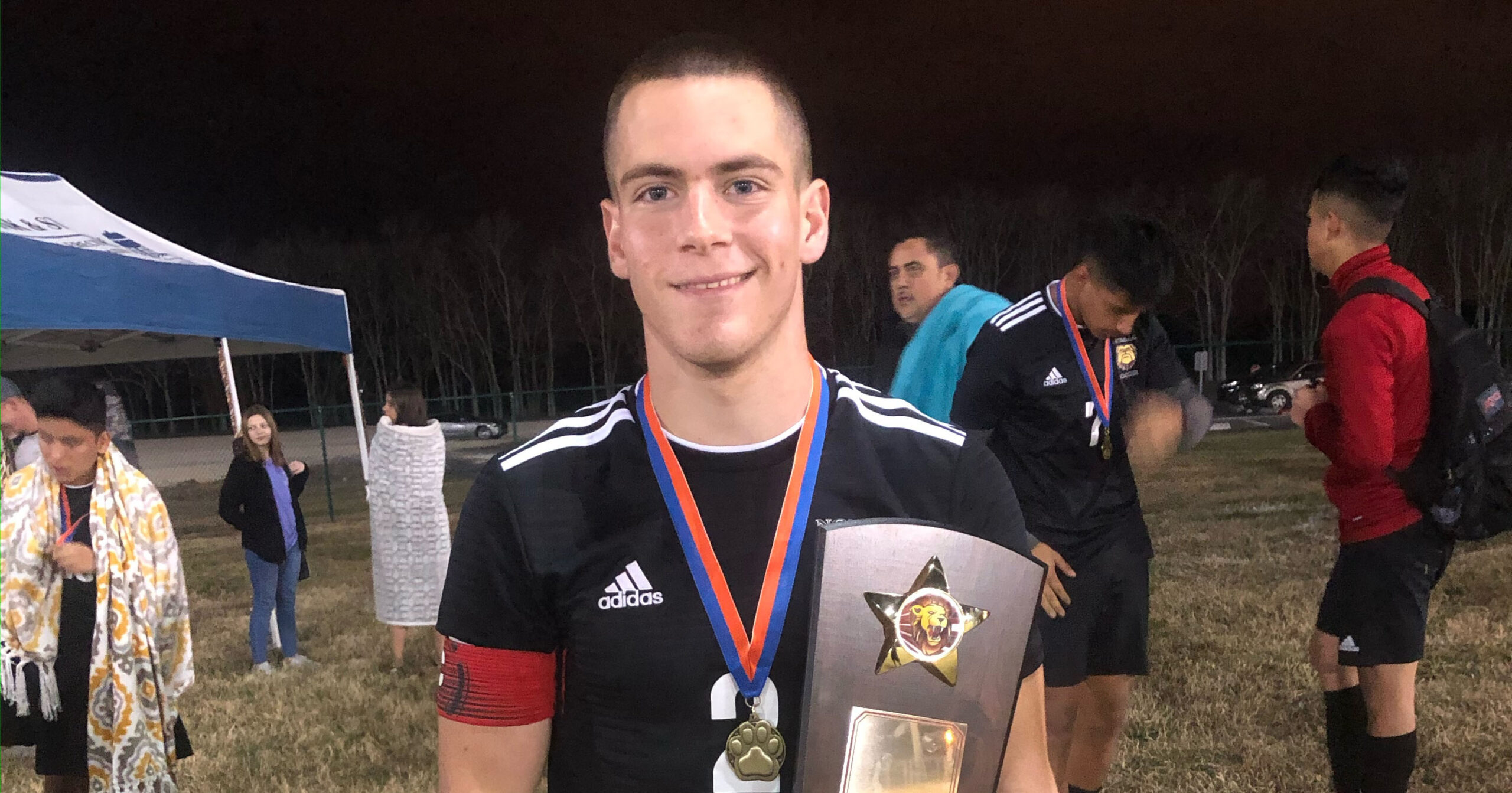 A soccer player holds an award after a match. 