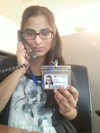 A woman sits on the phone while holding her ID badge.