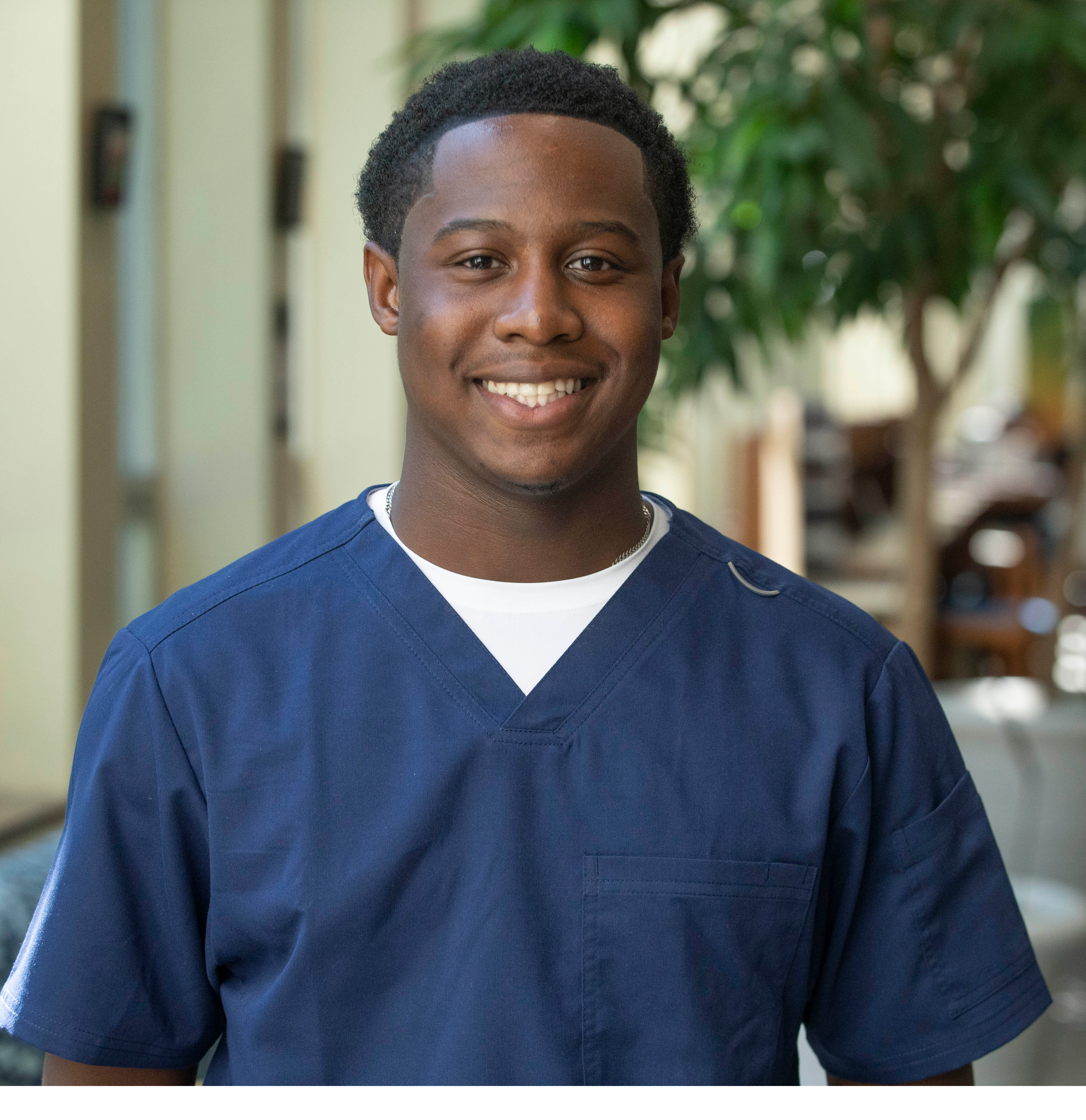Student smiling and wearing medical scrubs standing outdoors