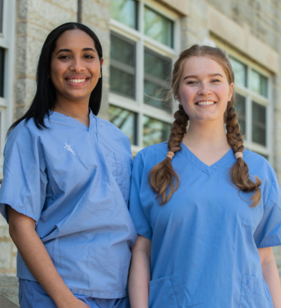 Pre-nursing students posing in front of academic building while wearing scrubs