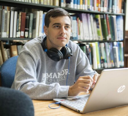 criminal justice student studying on his laptop on the library