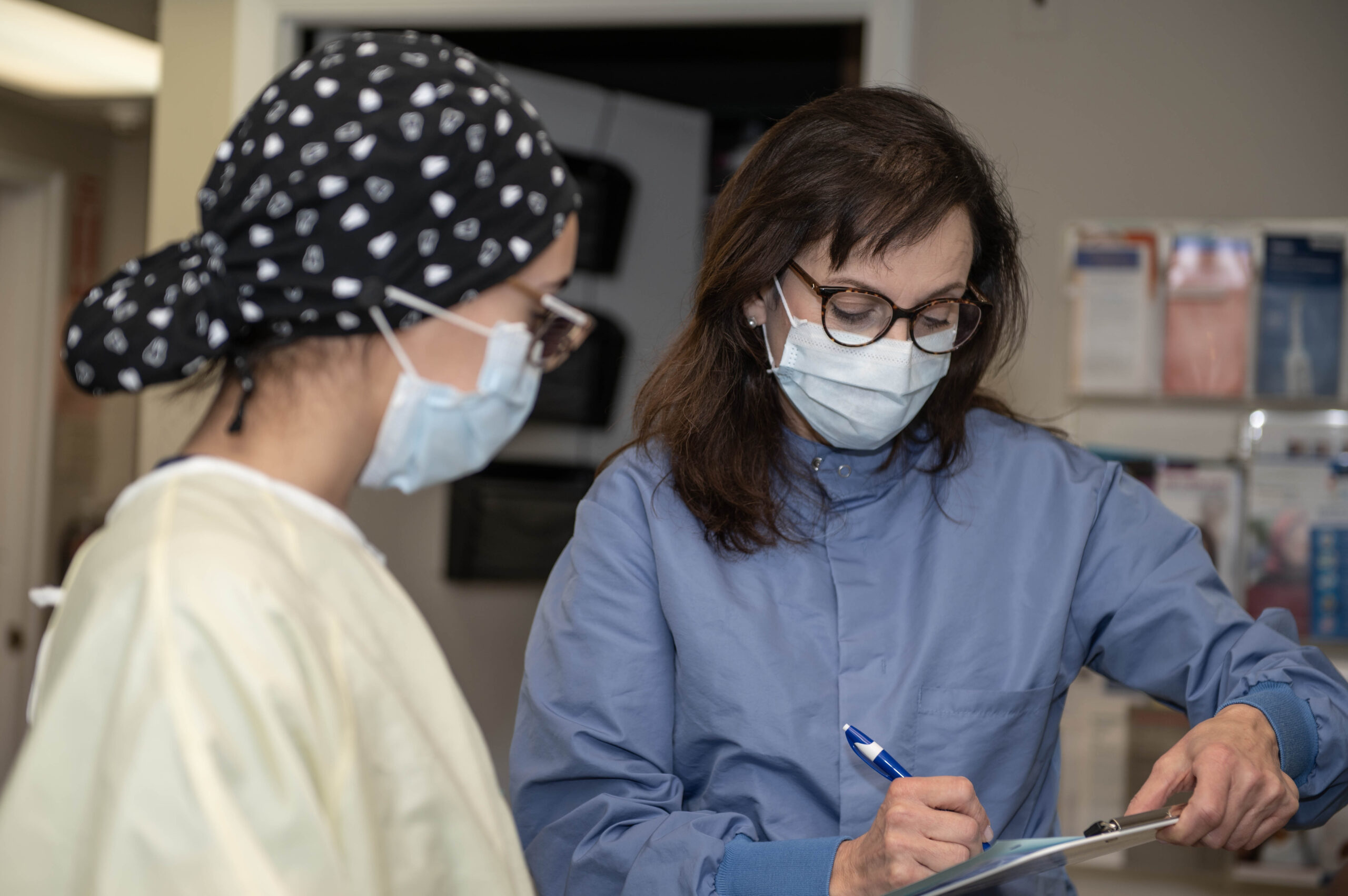 Two women in dental scrubs go over an examination in Manor College's Dental Health Center. 