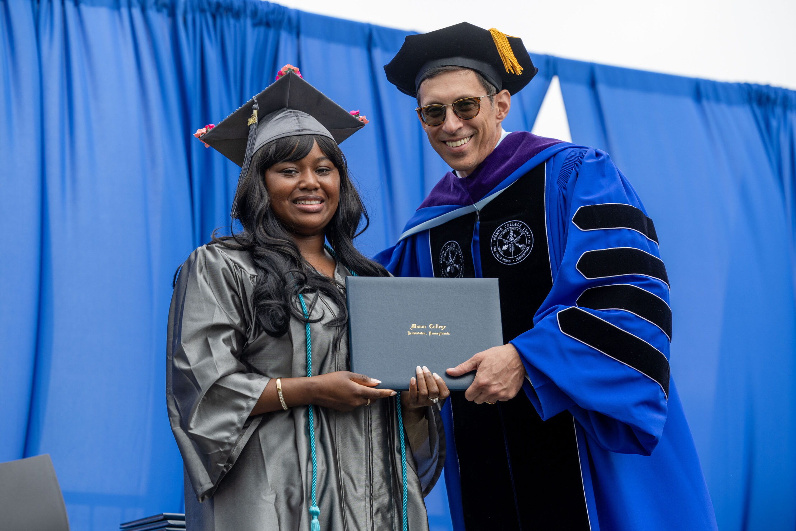 A woman in graduation regalia receives her diploma.